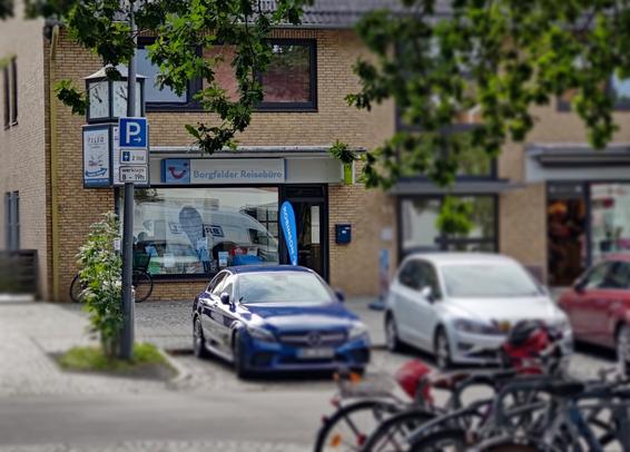 Parkende Autos neben Schild "Parkplatz" bis zu zwei Stunden mit Parkscheibe an Werktagen.