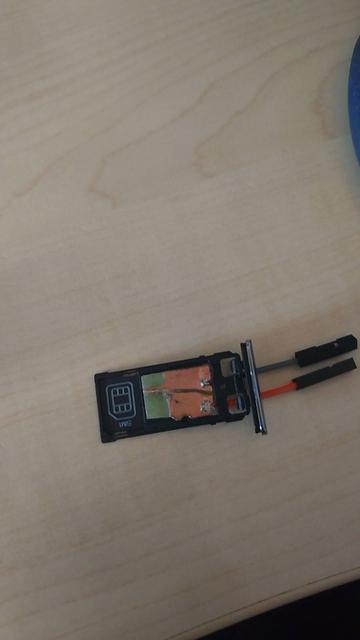 Photographie d'une fausse carte SD avec deux fils qui sortent, le tout dans le tiroir pour carte mémoire d'un Ordiphone.