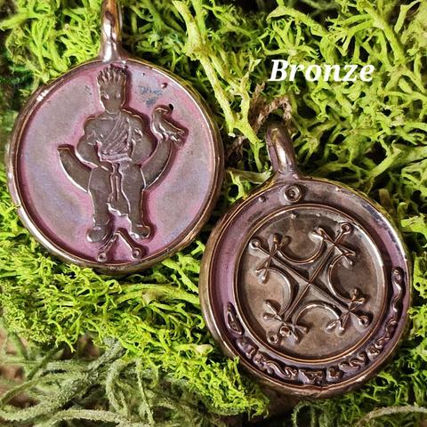 Image of a bronze solar talisman showing both the front and back. On the left is the obverse image, with a crowned figure sitting on a throne over a magical symbol, with a raven sitting at his left hand. On the right is the reverse image, with the Agrippan Grand Seal of the Sun in the center and the characters of the sun in an arc along the bottom.