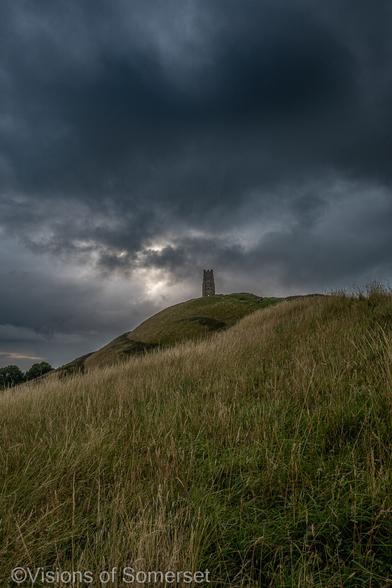 Grass in the foreground, dark clouds above the tower.