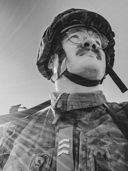 Mustavalkokuva minusta, kuvattu alaviistosta. Päälläni armeijan sotilasvarustus ja kypärä.