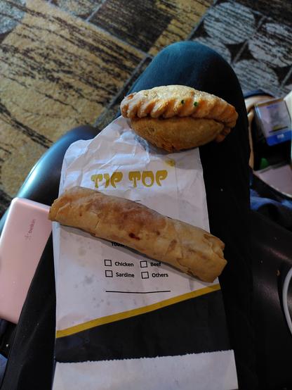 Eine Frühlingsrolle und Kartoffeltasche liegen auf meinem Schoß
