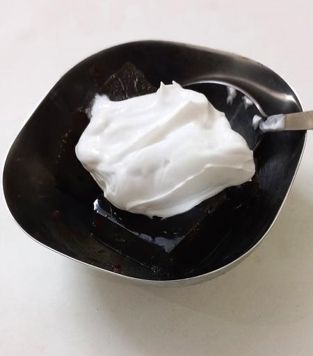 A small container with coffee jelly and whipped cream on top.