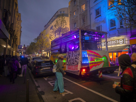 City Street scene at night featuring a stage set up in the road draped with anarchist banners