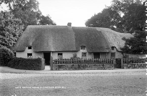 A black and white photograph taken between about 1880 and 1914 of a thatched gate cottage in Adare, Co. Limerick, Ireland.