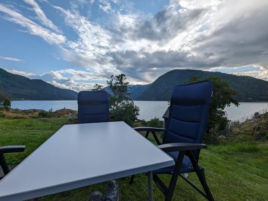 Camping table and chairs Infront of a fiord and mountain view