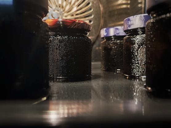 Vom Wasserdampf benetzte Schraubgläser, in denen die fertigen Schwarzen Nüsse im Backofen einkochen