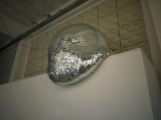 closer look at a big disco ball on a ledge above a doorway that appears to be melting.