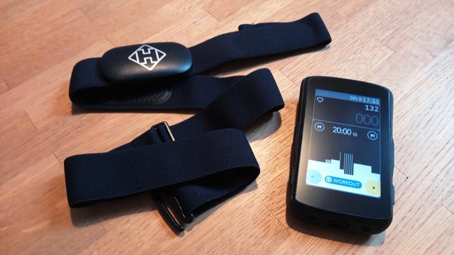 Einer die Herzfrequenz messender Brustgurt liegt neben einem Fahrrad-Navigationsgerät.