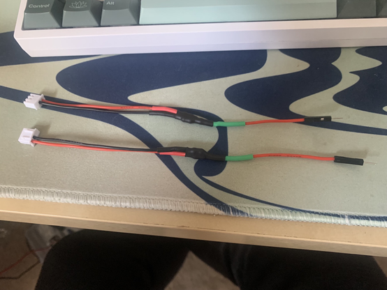 A mostly red and black cable, with 2 wires feeding into a connector on the left, and 1 wire into another connector on the right, connected in the middle by a couple of heat shrink tubes.
