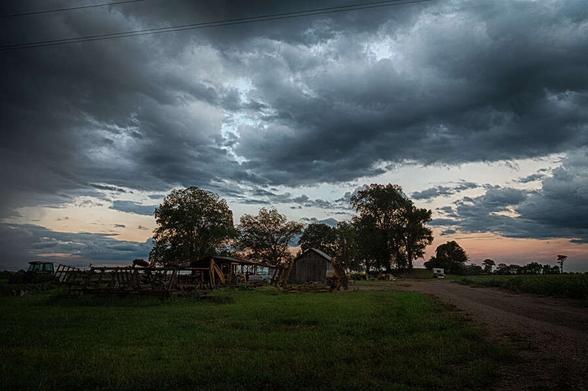 Road leading to farm buildings and an ancient earthwork mound at twilight. To the right of the buildings, with a tree growing out from it, is the mound built by the earliest people of the region. 

Attribution-NonCommercial 2.0 Unported (CC BY-NC 2.0) Richard May  https://creativecommons.org/licenses/by-nc/2.0/