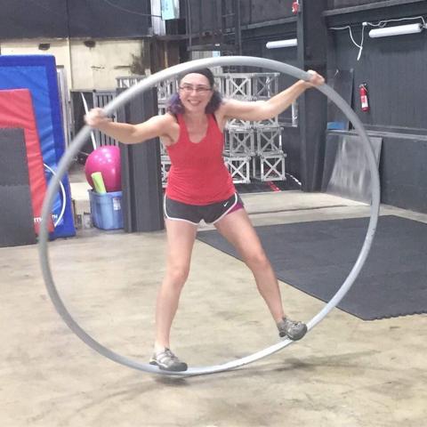 I am standing within a huge hoop, gripping the hoop with clenched fists and bent and tensed knees, looking like an awkward Vitruvian Man.