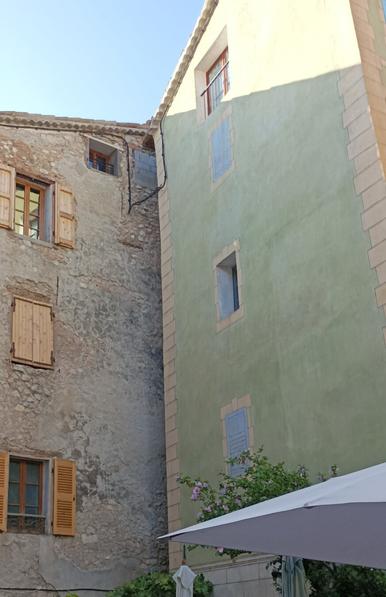 Two old, colourful stone-made buildings with taditional shutters