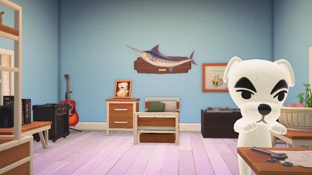 Animal Crossing: New Horizons screenshot. Happy Home Paradise setup of K.K. Slider's vacation home. The room has light blue wallpaper and white birch flooring. The room is designed to look like a bedroom with oak style ironwood furniture. The back left corner has an acoustic guitar and a speaker. The back right corner has a DJ station with records on the wall. K.K. can be seen facing the camera working at a ironwood workbench.