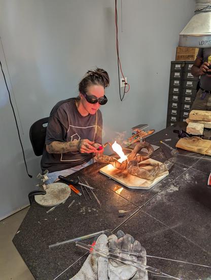 Meryl working on adding side tubulation candleholders with a hand torch.