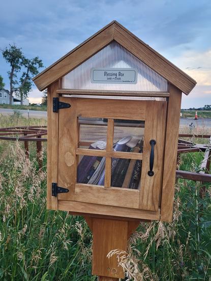 A small free library box surrounded by grass.