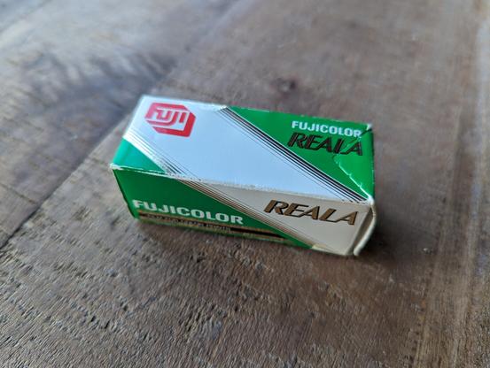 A roll of 120 Reala in a green and white box sitting on a wooden table..