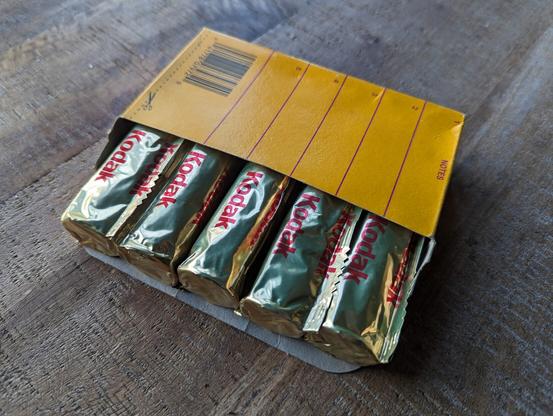 TMax 120 circa 1997 in classic gold foil in a yellow box on a wooden table.