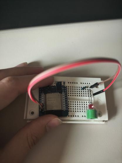 ESP32 connected to a red led on a breadboard with a resistor. Led is shining into a green, 3d-printed toslink socket taped to the breadboard