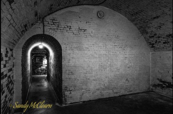 Passageway leaves end wall of underground room with arched ceiling  .