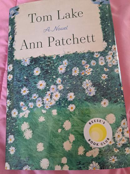 The book cover features a bed of flowers and grasses underneath title and author name.