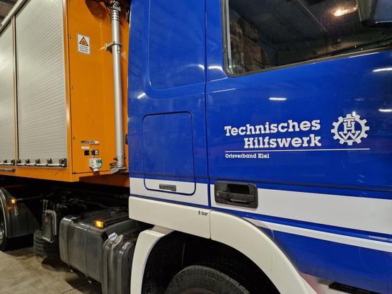 Wechsellader-Fahrzeug des Technischen Hilfswerkes (THW) in ultramarinblau mit einem Wechsellader-Container in orange