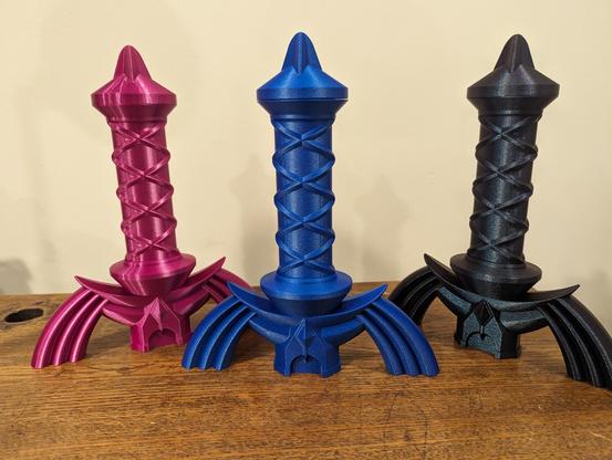 Three hilts of the master sword in magenta, blue and a darker greenish blue