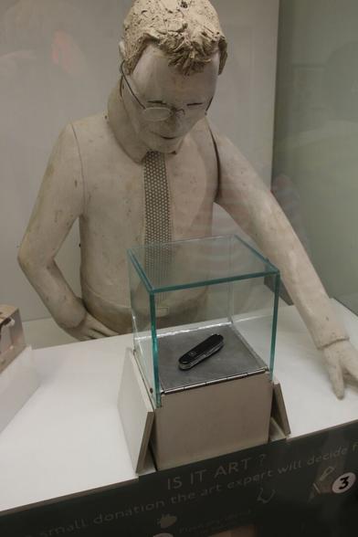 A near life size carved man (who looks rather like Tim Hunkin did when he was younger) peers intently at a glass box containing my Swiss Army penknife.