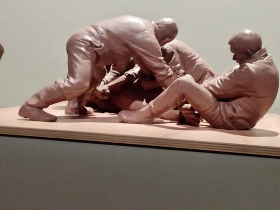 La même scène, vue sous un autre angle, qui souligne les pressions, torsions et étirements exercés à plusieurs sur ce corps allongé au sol, mais qu'on ne distingue pas en détail.