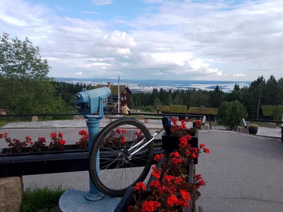 A view over Oslo from Frognerseteren. In the foreground is my unicycle resting by some potted flowers.