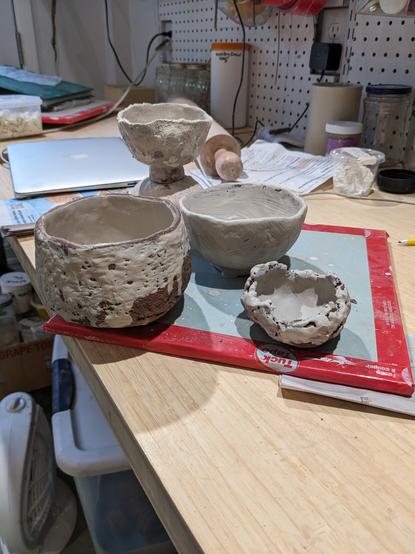 Four clay pieces, made by pinching a red clay, and painted with white slips. Tall footed cup in the back, a chawan on the left, a little bowl back right and a tiny one front right