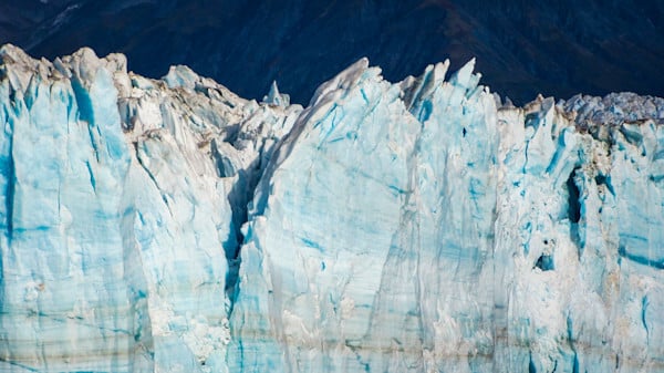 Jagged teeth of old glacial blue ice loom up from an ocean view