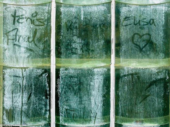 Glass windows of a hothouse in the botanical garden of Göttingen. Names and hearts written on the dirty glass.