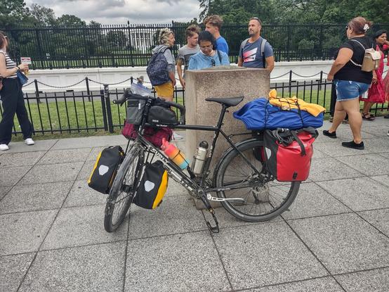 A loaded touring bike leaning against the Zero Mile Marker for roads with the White House in the background.