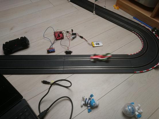 Un montage électronique près d'un circuit de voiture électrique pour enfant, permettant de mesurer la durée d'un tour