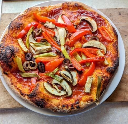 A pizza topped with sliced mushrooms and red and green vegetables.