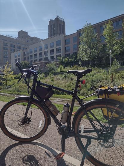 A bicycle parked on the Minneapolis Greenway with the Midtown Market building in the background