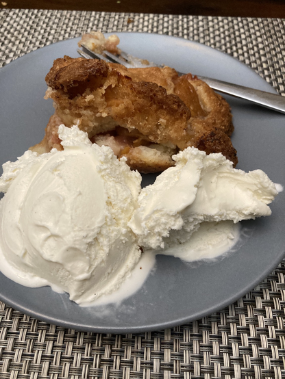Peach cobbler with vanilla ice cream on a blue plate