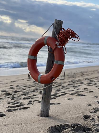 Life belt hanging on a  post ready to be used in case of emergency at the beach of Saubaudia. In the background a cloudy heaven and the rough waves of the ocean.