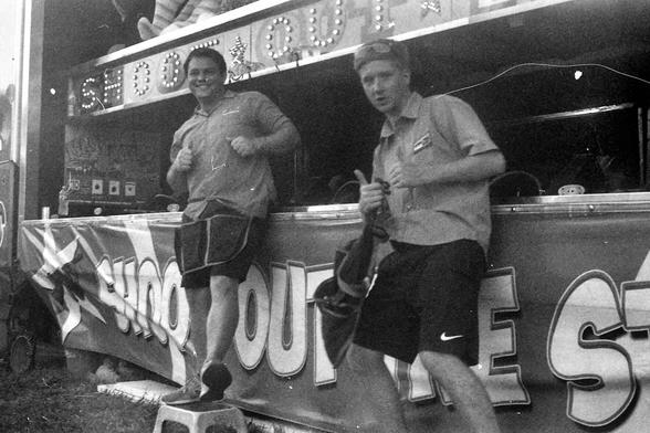 Black and white photograph of two carnival employees giving thumbs up