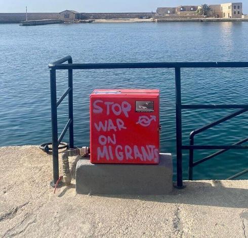 "Stop war on migrants" written on a signal box with purple marker