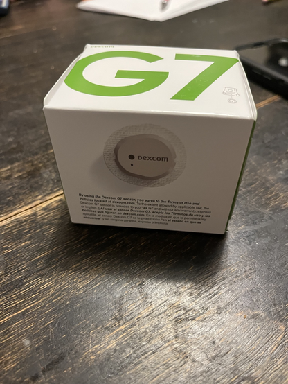 Image shows a box containing a Dexcom G7 sensor sitting on a wooden table