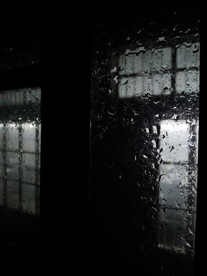 Raindrops on window glass at night.
