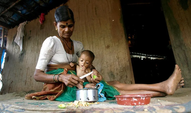 Very thin woman feeding her grandchild