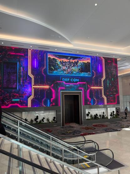 Image shows the inside of a Casino with the wall decorated electric colors with a sign for the conference called DEFCON