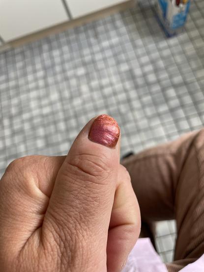 Pic of my left thumb with a orange/pink/glitter polished nail