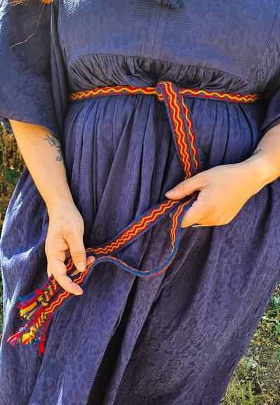 A hand woven trim made on a rigid heddle loom and tablet weaving technique, using merino wool in red, blue and yellow.