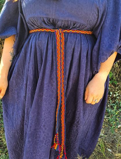 A hand woven trim made on a rigid heddle loom and tablet weaving technique, using merino wool in red, blue and yellow.