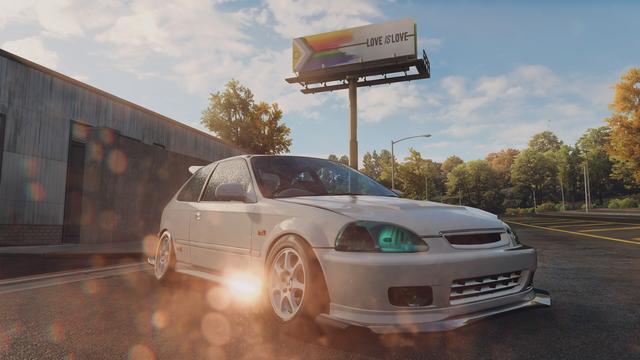 My EK9 parked in front of a billboard with a pride flag on it.