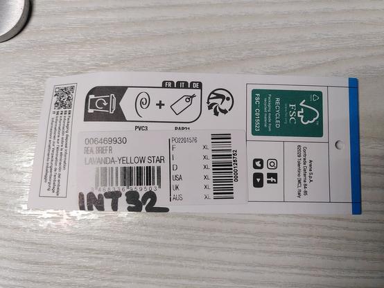 A clothing tag where someone wrote "INT32" with a black marker.